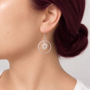Boucles d'oreilles Soleil Sira en acier inoxydable argenté avec pendentif soleil ajouré.