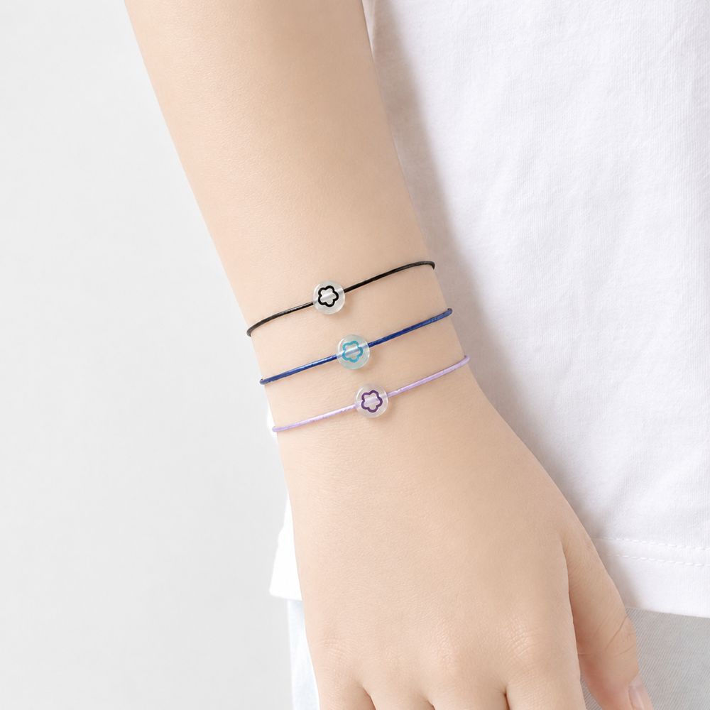 Bracelet enfant Fleur Lumineuse Faria Minia en acier inoxydable avec fleur phosphorescente et cordon ajustable.