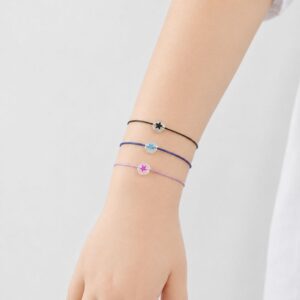 Bracelet enfant Étoile Lumineuse Eliza Minia en acier inoxydable avec étoile phosphorescente et cordon ajustable.